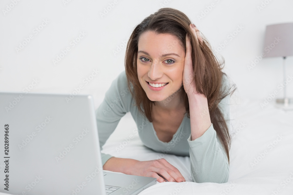 Relaxed casual smiling woman using laptop in bed Relaxed casual smiling woman using laptop in bed