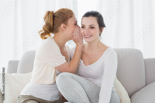 Happy female friends gossiping in living room