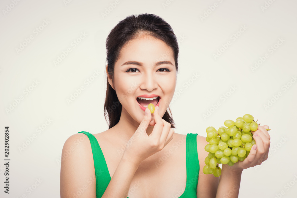 Young beautiful asian woman eating fresh grapes isolated on white background Young beautiful asian woman eating fresh grapes isolated on white background