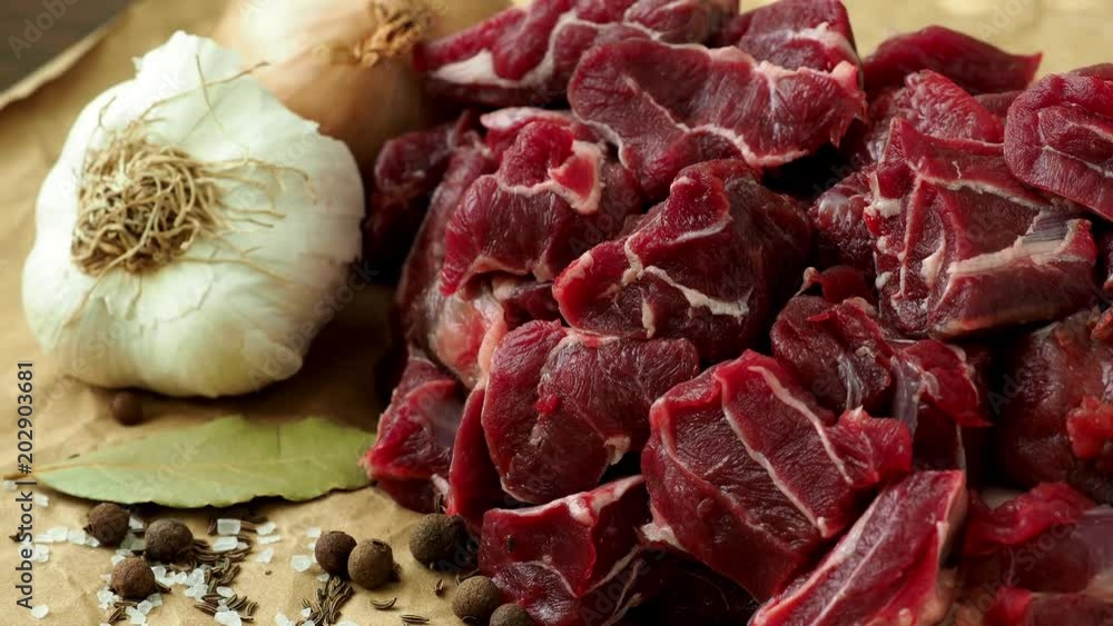 Raw beef meat with spices on paper Raw beef meat with spices on paper
