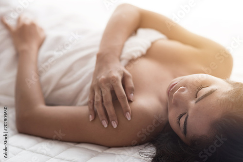 Young woman in bedroom sensuality concept lying touching shoulder