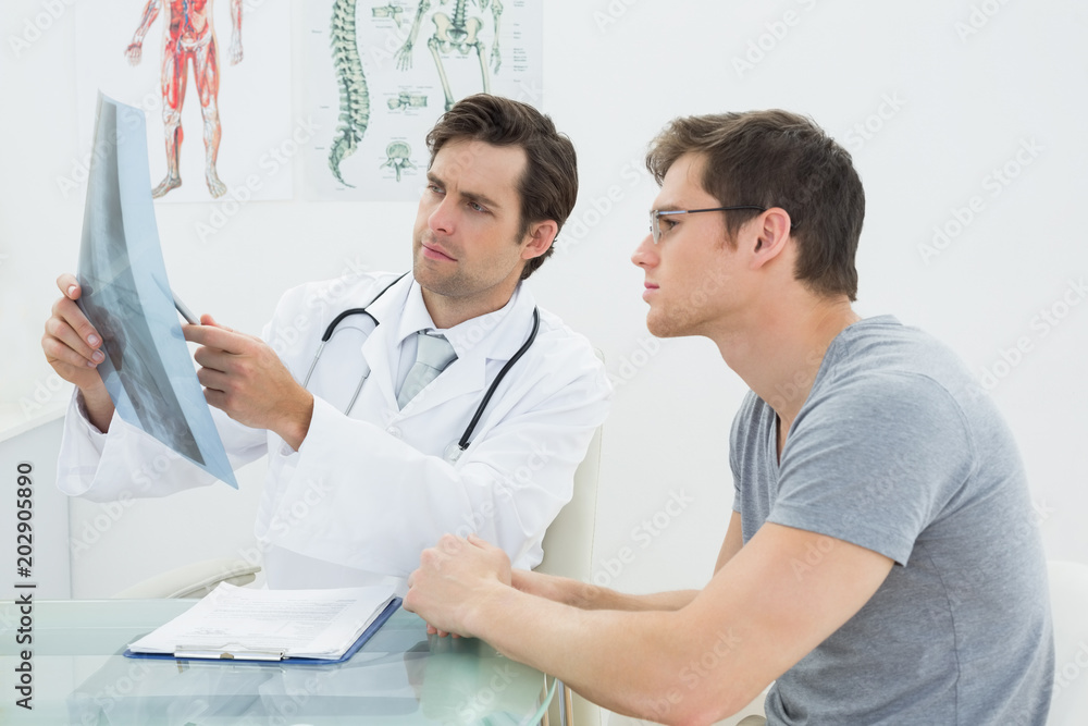 Obraz premium Male doctor explaining spine xray to patient