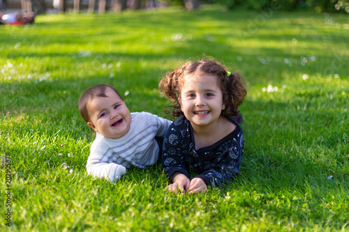 Two sisters playing in the grass in a park © jos_persona