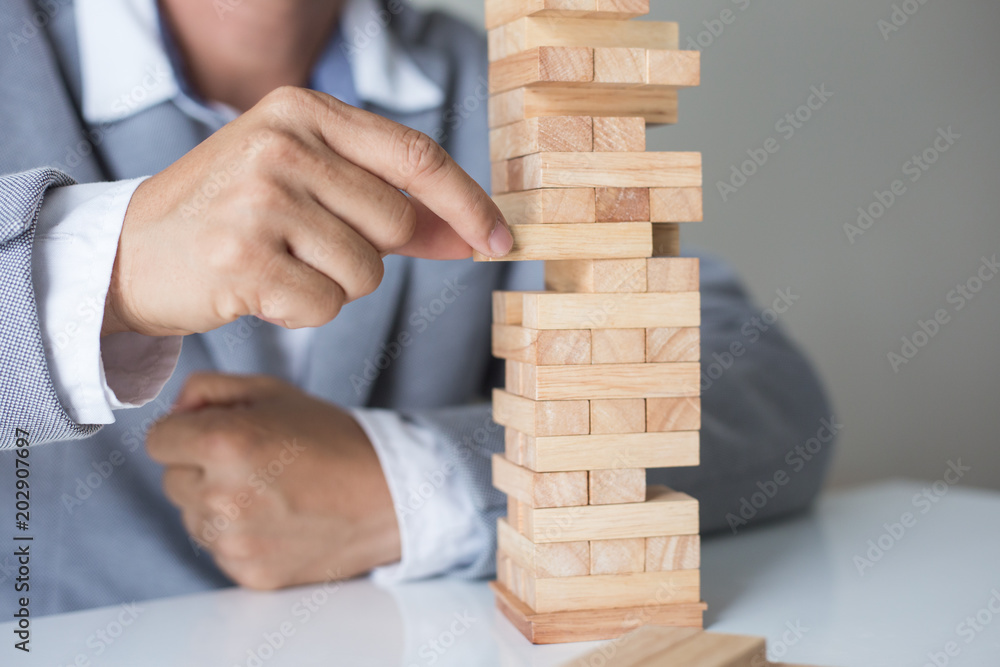 Planning, risk and strategy in business, businessman and engineer gambling placing wooden block on a tower. Planning, risk and strategy in business, businessman and engineer gambling placing wooden block on a tower.