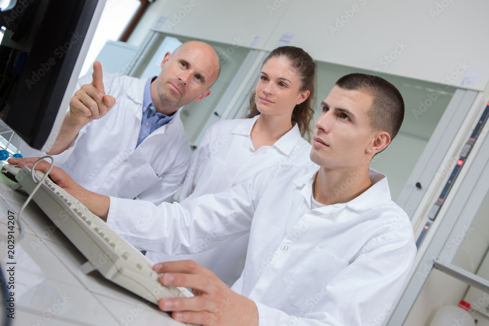 Young scientist working on computer, teacher pointing to screen Young scientist working on computer, teacher pointing to screen