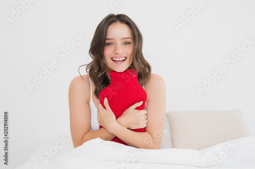 Smiling woman with a hot water bottle in bed photo