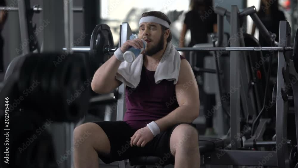 Thirsty happy man drinking water after exhausting training, weight loss workout Thirsty happy man drinking water after exhausting training, weight loss workout