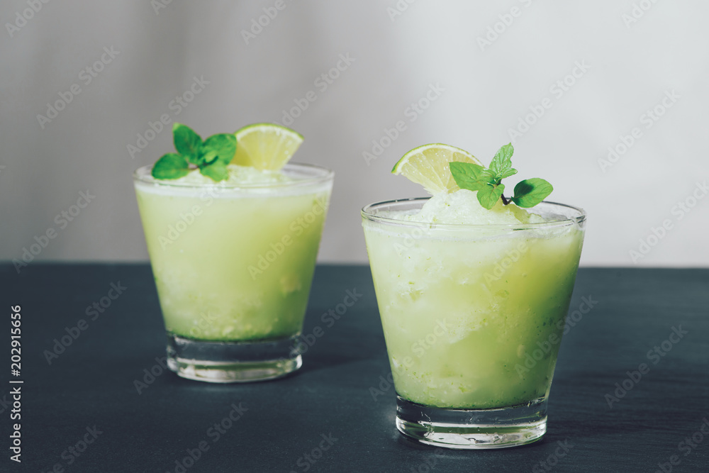 Cocktail juice with lime, mint and ice. Bar drink accessories on black table background. Cocktail juice with lime, mint and ice. Bar drink accessories on black table background.