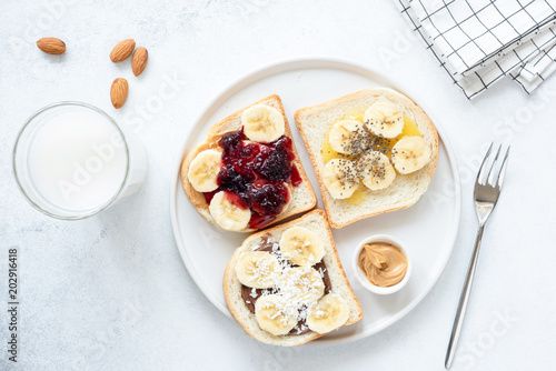 Vegan or vegetarian bread, nut butter, jam and chia seed toast. Healthy breakfast, healthy lunch toast with nut butter and banana. Flat lay, healthy lifestyle concept. Top view