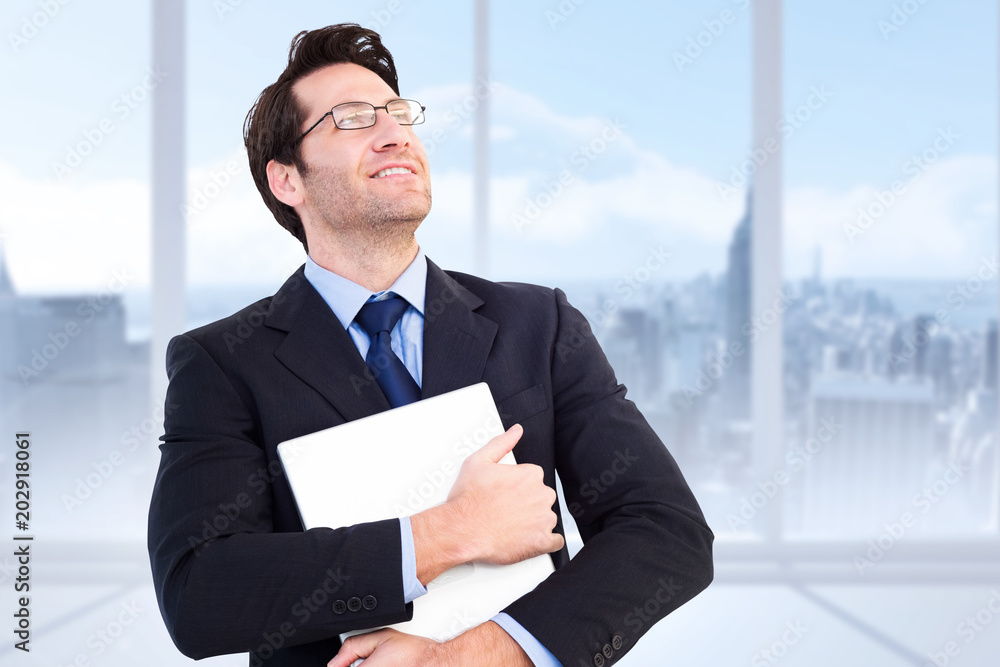 Handsome businessman holding his laptop against bright white room with windows Handsome businessman holding his laptop against bright white room with windows