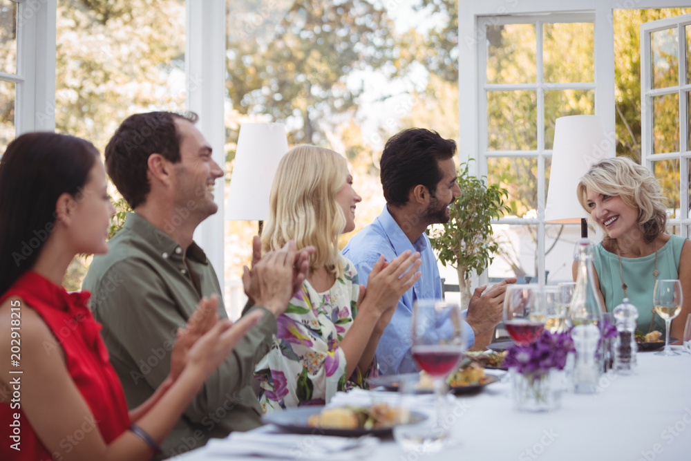 Group of friends interacting with each other while having meal together Group of friends interacting with each other while having meal together