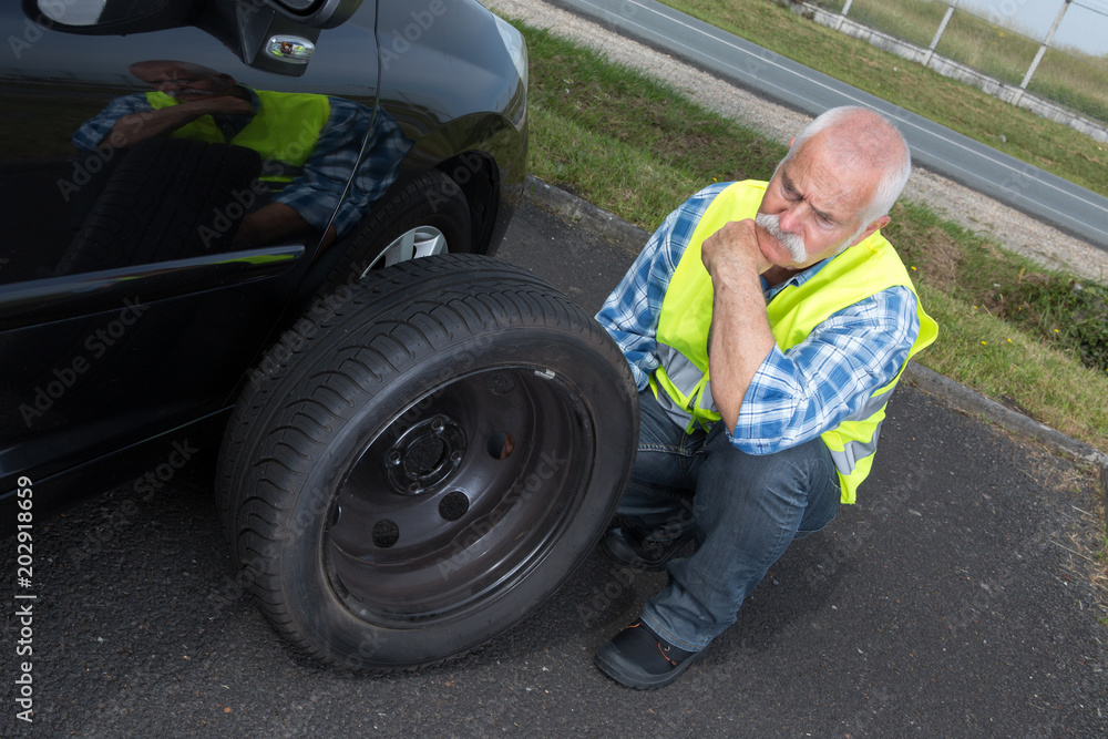 discouraged retired man unable to change car tyre