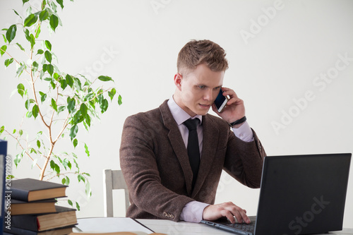 a man in a business suit works at a desk with a computer and books in the Office photo