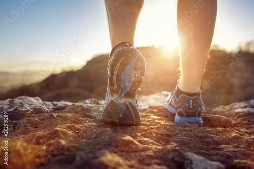 Runner feet running on trail looking at sunset photo