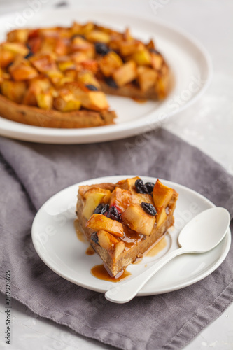Vegan apple pie with cinnamon, raisins and caramel, gray background, vertical