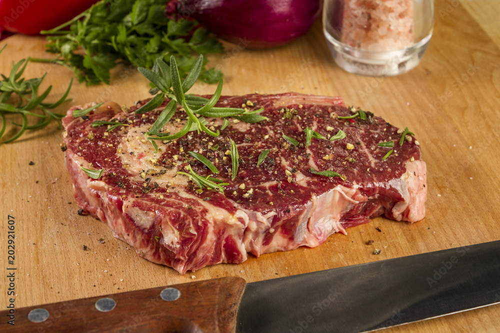 Ripened seasoned beef rib eye or entrecote steak on wooden cut board prepared for cooking