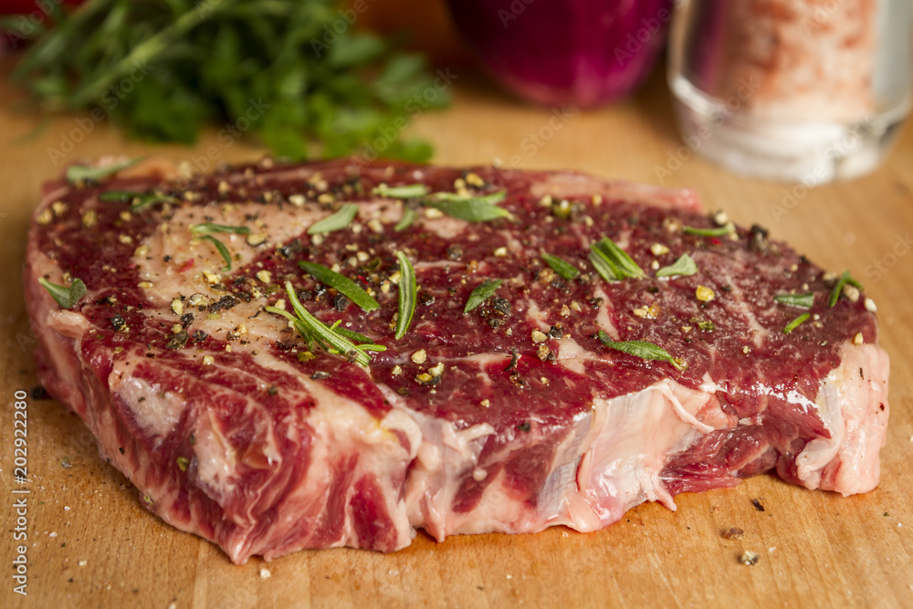 Ripened seasoned beef rib eye or entrecote steak on wooden cut board prepared for cooking