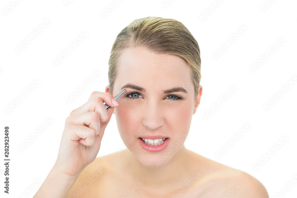 Suffering attractive blonde using tweezers on her eyebrow