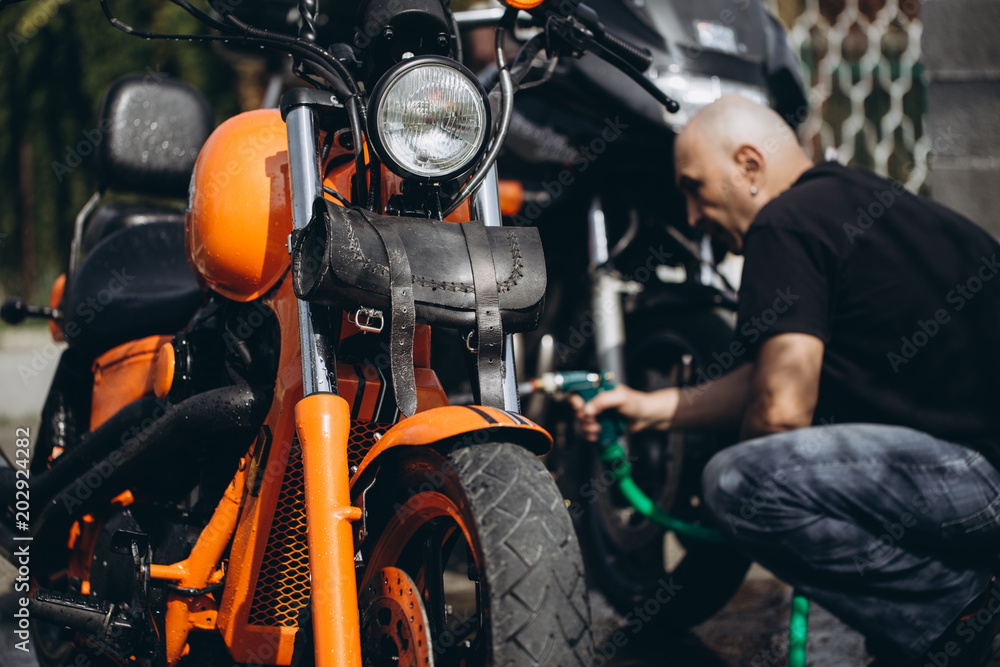 Adult and experienced biker cleaning and washing his motorcycle Adult and experienced biker cleaning and washing his motorcycle