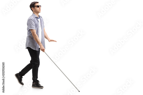 Blind young man with a cane walking