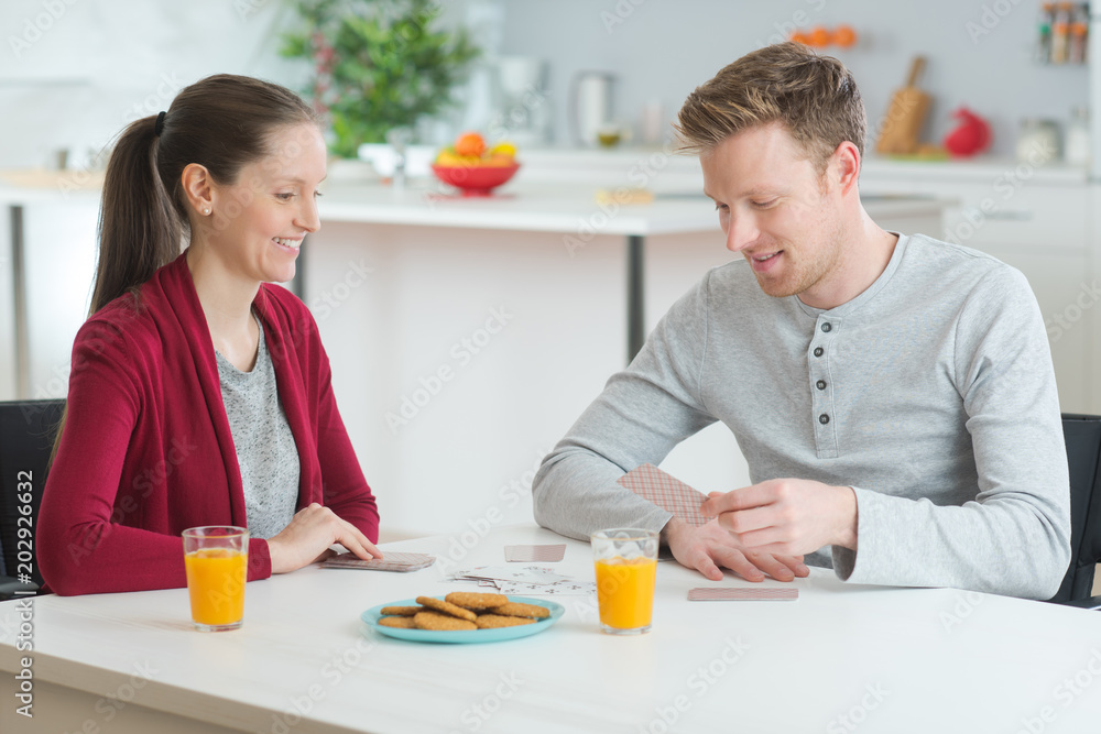 young couple playing cards while having breakfast in kitchen young couple playing cards while having breakfast in kitchen