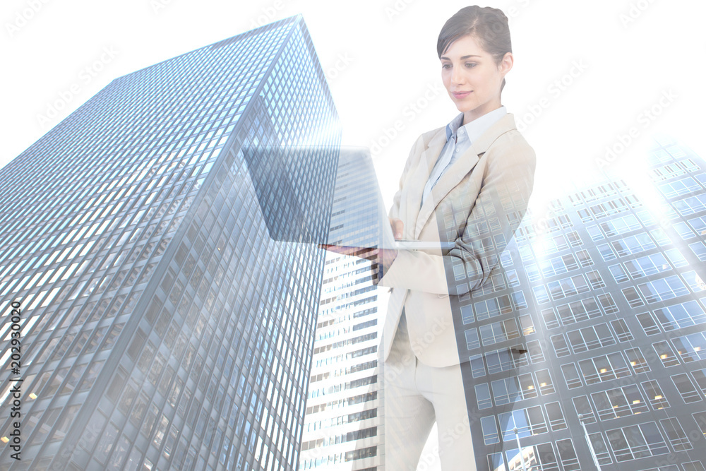 Confident businesswoman holding laptop against low angle view of skyscrapers Confident businesswoman holding laptop against low angle view of skyscrapers