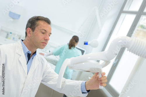 male orthodontist adjusting the controls on a panoramic imager