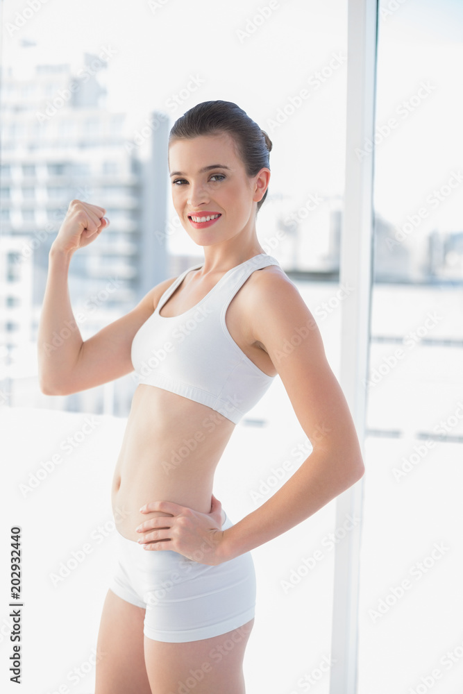 Motivated fit brown haired model in sportswear showing her muscles