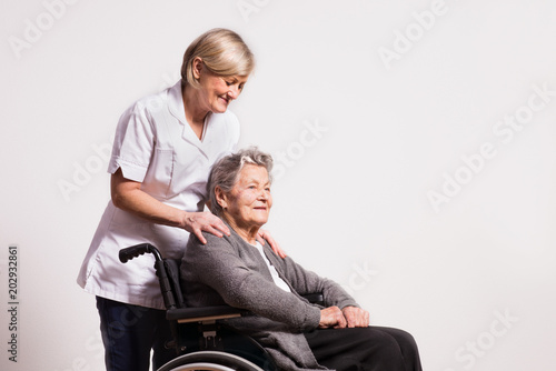 Studio portrait of a senior woman in wheelchair and a nurse. © Halfpoint