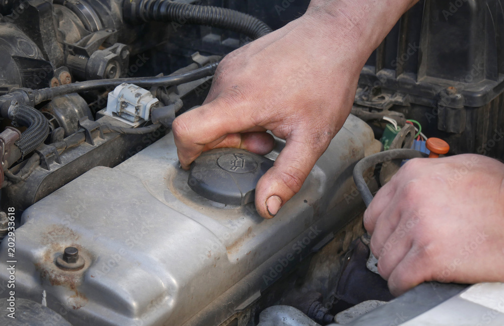 Mechanic opening oil cap of car engine, closeup of hand Mechanic opening oil cap of car engine, closeup of hand