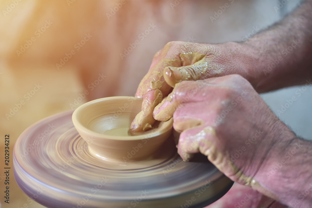 Creating a jar or vase of white clay close-up. Man hands, pottery, workshop, ceramics art concept. Twisted potter's wheel