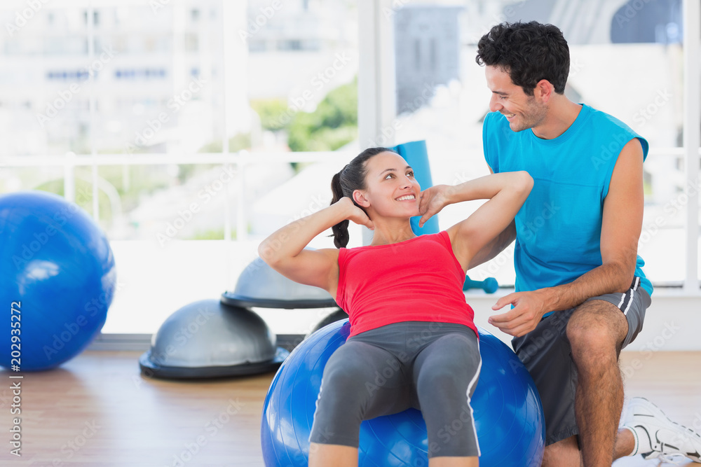 Male trainer helping woman with her exercises at gym Male trainer helping woman with her exercises at gym