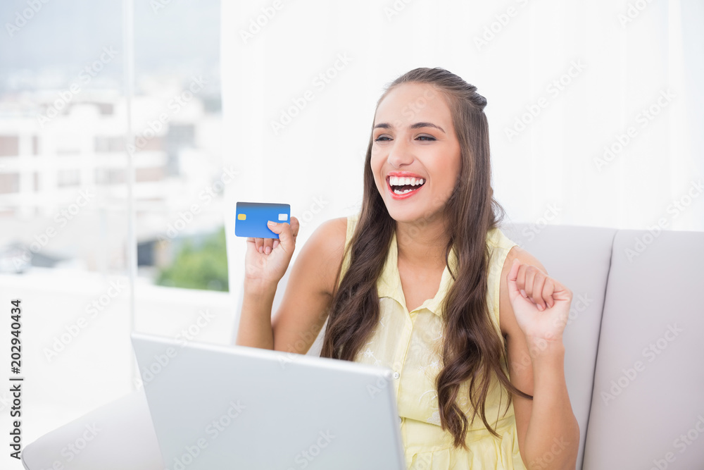 Victorious young brunette holding credit card Victorious young brunette holding credit card
