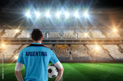 Argentina football player holding ball against stadium full of argentina football fans