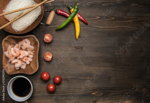 Preparation of Funchoza with shrimps, hot peppers, tomatoes and soy sauce, on rustic wooden background, space for text