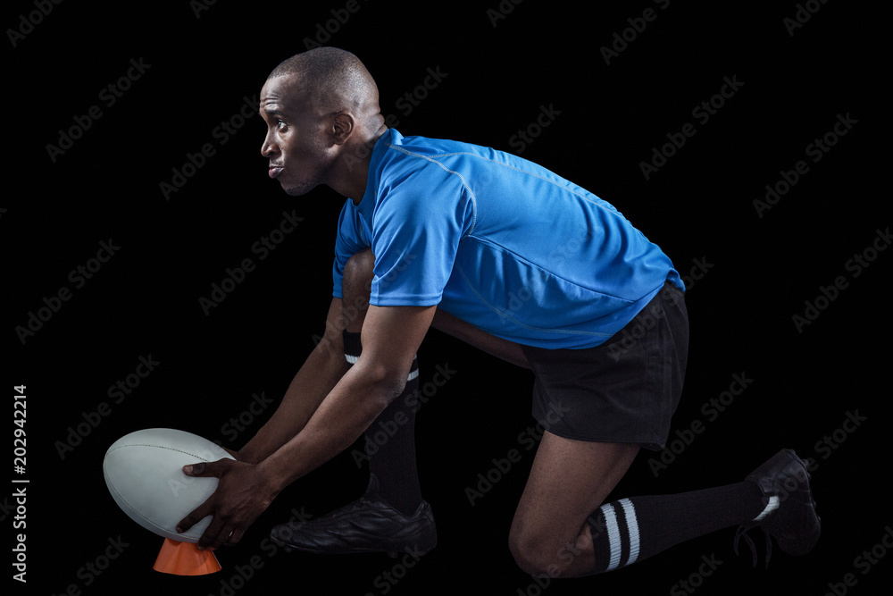 Confident rugby player looking away while keeping ball on kicking tee