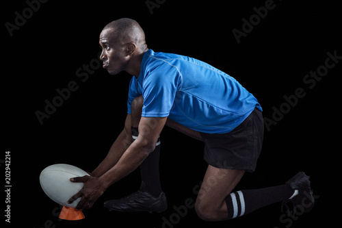 Confident rugby player looking away while keeping ball on kicking tee