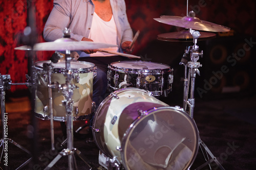 Mid section of drummer performing on stage at nightclub