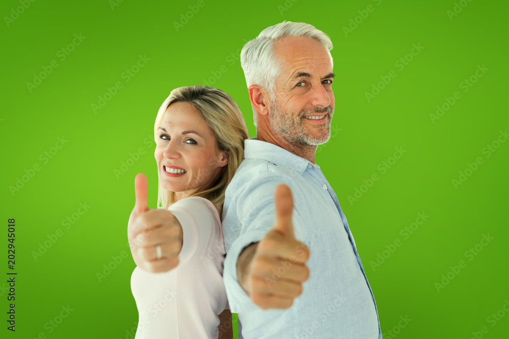 Smiling couple showing thumbs up together against green vignette Smiling couple showing thumbs up together against green vignette