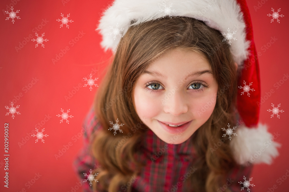 Happy little girl in santa hat against snowflakes Happy little girl in santa hat against snowflakes