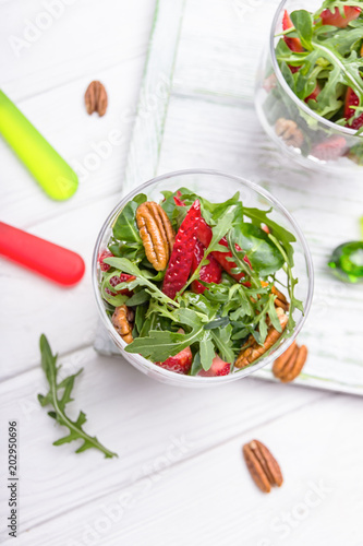 Homemade salad with strawberries, pecan nuts and arugula on a white background. Top view