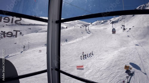 4K. View from inside a gondola lift going up a snowy mountain on a ski resort. There are people skiing in the snowy slope. Sierra Nevada, Spain-Adrian.