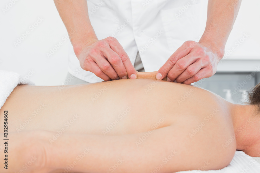 Mid section of a physiotherapist massaging womans back Mid section of a physiotherapist massaging womans back