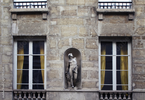 View of a statue / sculpture placed on the facade of a building in Saint-Germain area of Paris showing French / Parisian architectural style.