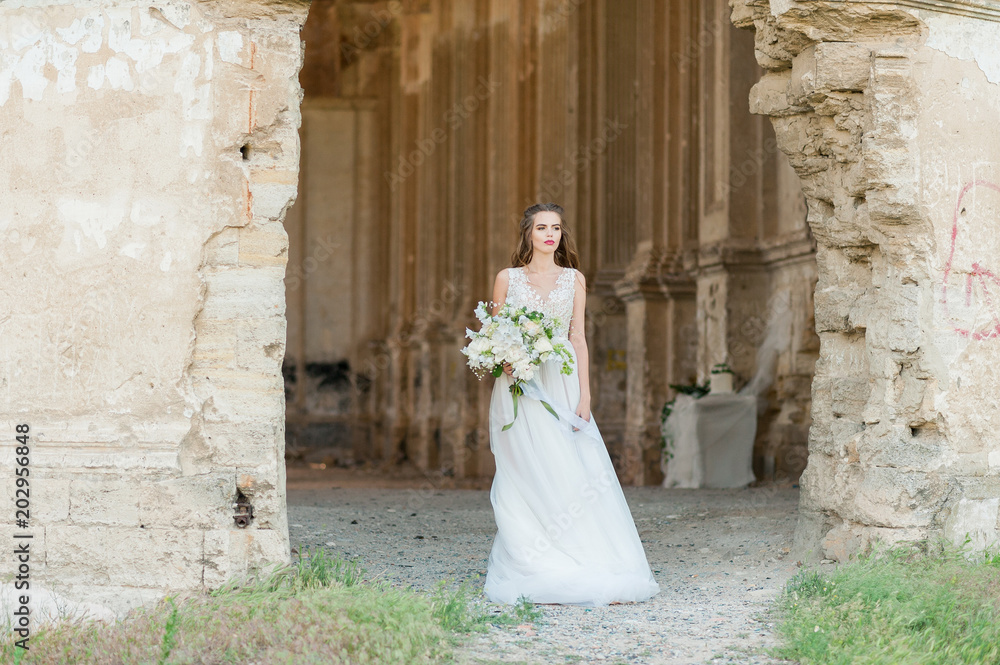 Fototapeta premium Romantic beautiful bride in luxury dress posing of beautiful architecture