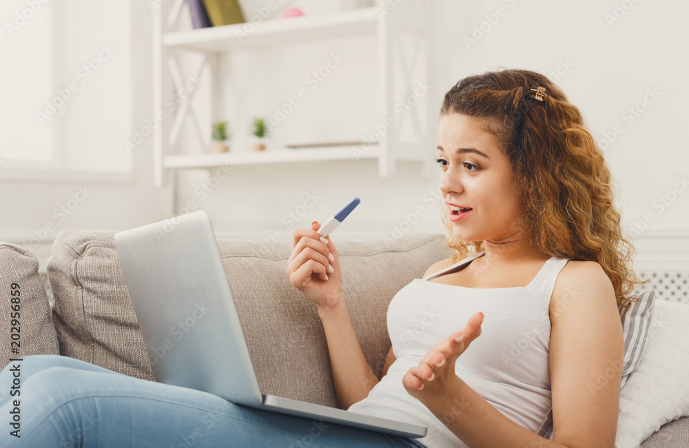 Woman browsing on laptop with pregnancy test Woman browsing on laptop with pregnancy test
