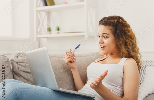Woman browsing on laptop with pregnancy test