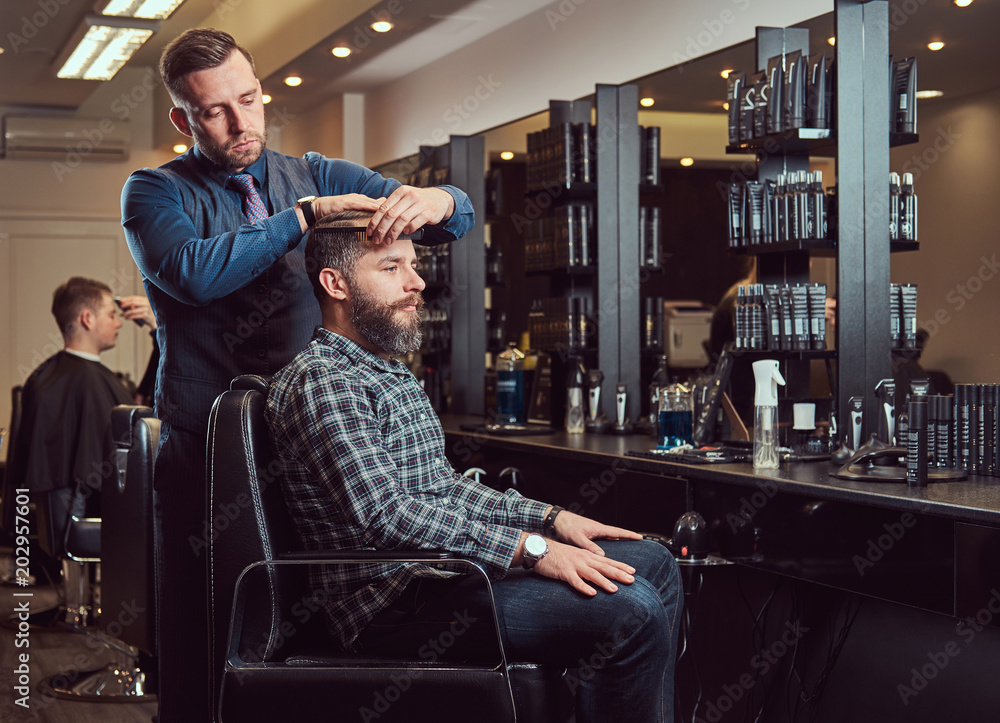A stylish Master barber does a haircut to the client. Men's haircut in a barbershop. A stylish Master barber does a haircut to the client. Men's haircut in a barbershop.