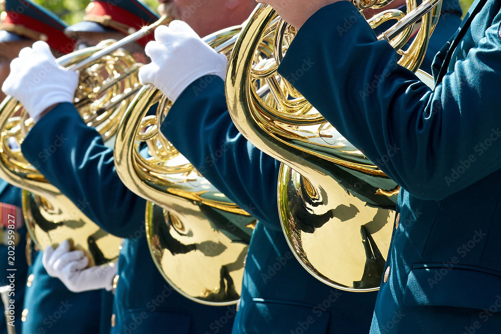 Φωτογραφία Closeup of military musicians in green uniform and white gloves playing a French horn during a parade in the street