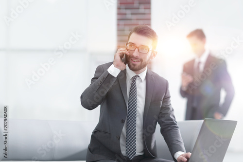 Confident young man talking on phone in office